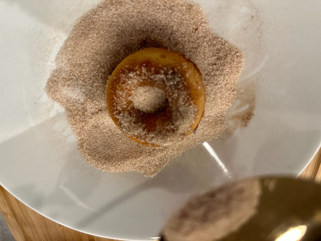 Obalování skořicových donutů ve skořicovém cukru